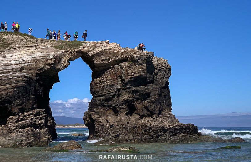 Turistas subidos a lo alto de una de las rocas en la Playa de las Catedrales, Galicia